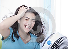 Beautiful young teen enjoying cool fan breeze photo