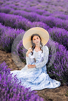 Beautiful young teen girl outdoors portrait. Brunette in hat with basket flowers harvesting in lavender field Provence, at sunset