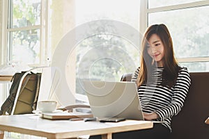 Beautiful young teenage woman freelance work with laptop at coffee shop in with sun light, freelance lifestyle