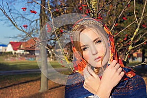 Beautiful young tender graceful girl in colored scarf on her head with a beautiful gold band with a gentle makeup stands