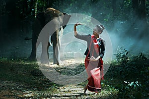 Beautiful young Thai woman northeast style is enjoy dancing and playing with elephant in the jungle