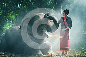 Beautiful young Thai woman northeast style is enjoy dancing and playing with elephant in the jungle photo