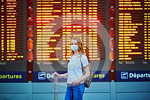 Beautiful young tourist girl with backpack and carry on luggage in international airport