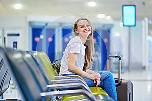 Beautiful young tourist girl with backpack and carry on luggage in international airport