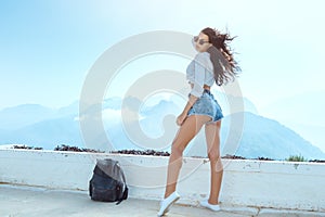 Beautiful young tourist girl with backpack at mountains