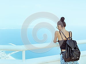 Beautiful young tourist girl with backpack near sea