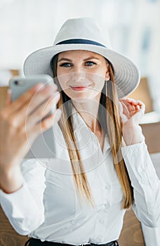 Beautiful young tourist girl in international airport, taking funny selfie with passport and boarding pass near flight