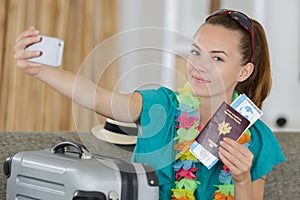 Beautiful young tourist girl taking funny selfie with passport