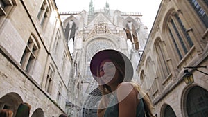 Beautiful young tourist girl woman feels free, happy smiling, the backdrop of the cathedral. Concept: tourism, love to