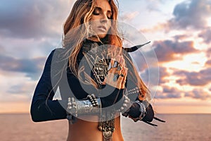 Beautiful young tribal style woman holding hands pray namaste on the beach at sunset