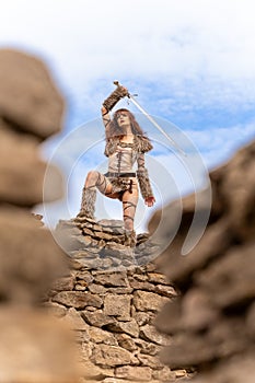 Beautiful young viking warrior woman with sword  scouting the land from the castle wall preparing for battle