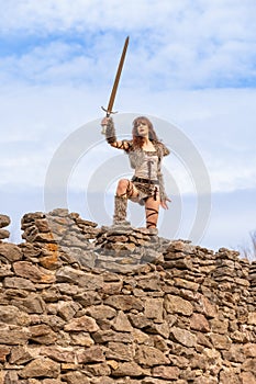 Beautiful young viking warrior woman with sword  scouting the land from the castle wall preparing for battle photo