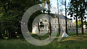 Beautiful young wedding couple softly kiss in the green forest. Beautiful renaissance old castle on the background