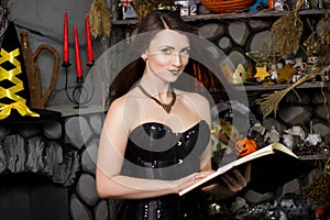 witch in a black corset with a book in his hands conjures reads a spell. Girl in costume on halloween photo