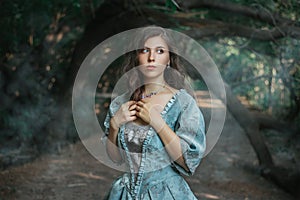 Beautiful young woman in 18-19 century dress and white gloves in the forest by the pond. Girl in a mysterious forest. The photo