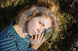 Beautiful young woman 18 years old lies on the green moss in the forest, enjoying the sunlight. outdoor recreation