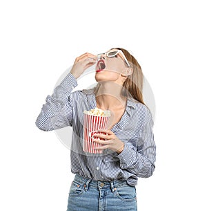 Beautiful young woman with 3D cinema glasses eating popcorn on white background