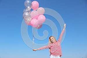 Beautiful young woman with air balloons against blue sky