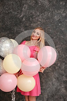 Beautiful young woman with air balloons on dark background