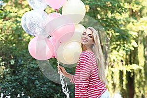 Beautiful young woman with air balloons in park