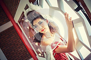 Beautiful young woman with angle wings of red dress posing near