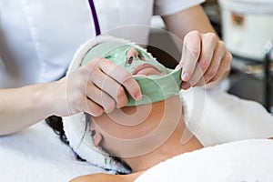 Beautiful young woman with antiaging facial mask in spa.