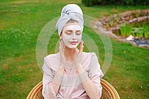 Beautiful young woman applied mask on her face with towel on her head