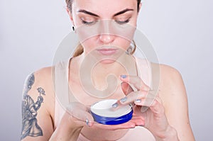 Beautiful young woman appliyng facial moisturizing cream.