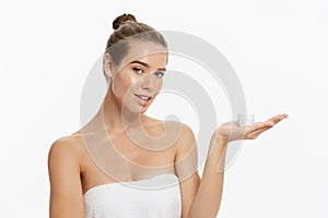 Beautiful young woman applying cosmetic cream treatment on her face isolated on white background