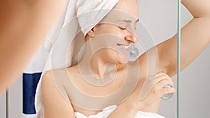 Beautiful young woman applying deodorant at bathroom after having shower. Concept of hygiene, natural beauty, feminity and body