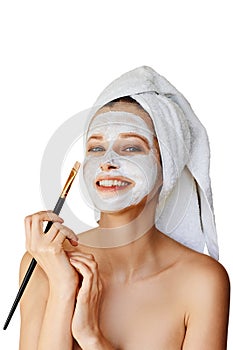 Beautiful young woman applying facial mask on her face with brush. Skin care and treatment, spa, natural beauty and cosmetology