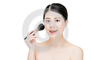 Beautiful young woman applying foundation powder blush with make