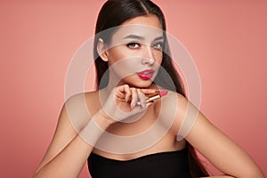 A beautiful young woman applying lipstick