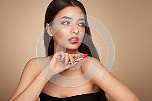 A beautiful young woman applying lipstick