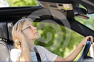 beautiful young woman applying make-up while driving car