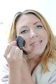 Beautiful young woman applying makeup