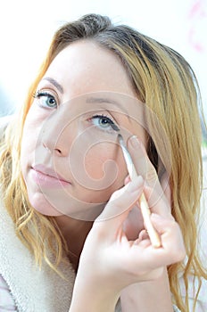 Beautiful young woman applying makeup