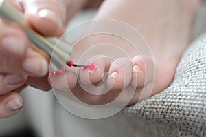 Beautiful young woman applying nail paint