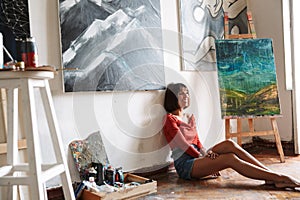 Beautiful young woman artist sitting in the art studio