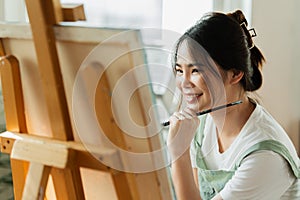 A beautiful young woman artist working on painting something on a large canvas
