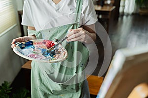 A beautiful young woman artist working on painting something on a large canvas