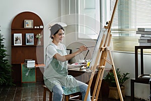 beautiful young woman artist working on painting something on a large canvas