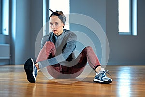 Beautiful young woman athlete tying shoelaces on sneakers while relaxing from strength training in the gym. oncept of