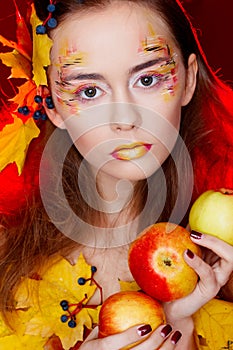 Beautiful young woman with autumn make up holding apples in her
