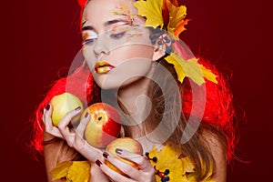 Beautiful young woman with autumn make up holding apples in her