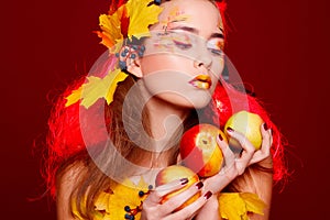 Beautiful young woman with autumn make up holding apples in her