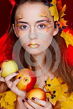 Beautiful young woman with autumn make up holding apples in her