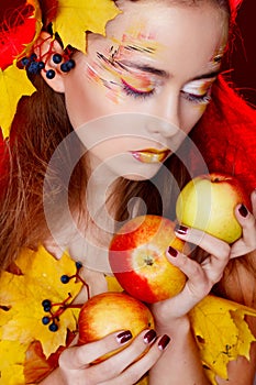 Beautiful young woman with autumn make up holding apples in her