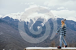 Beautiful young woman on  background of snowy mountains. Winter holidays travel. Copy space