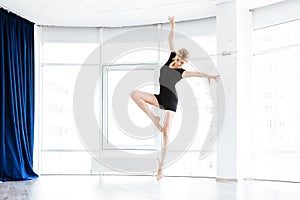 Beautiful young woman ballerina dancing and jumping in ballet school